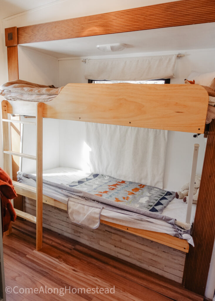 bunkbeds in rv with ladder, side rail at the top, and retractable side rail at the bottom