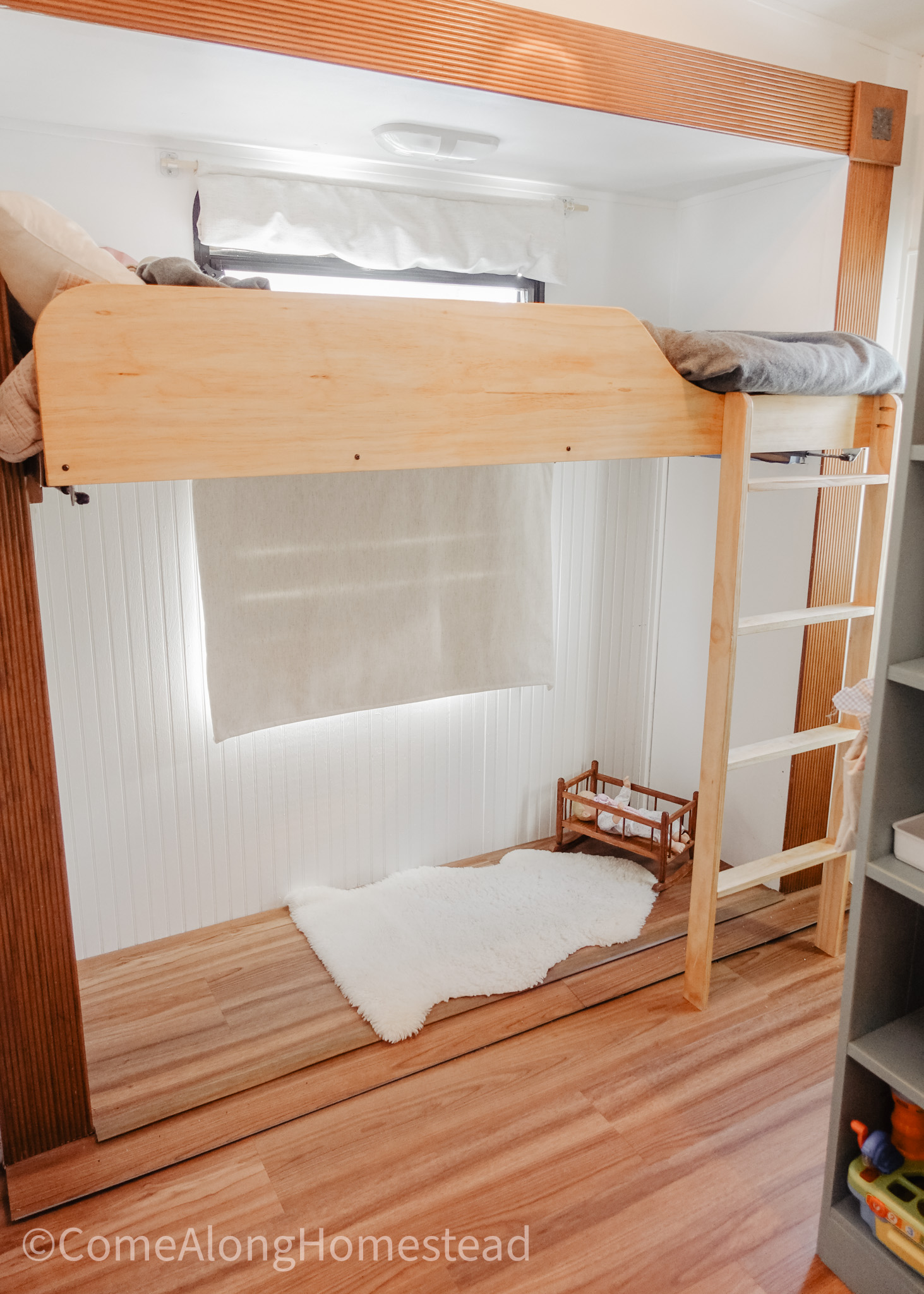 top bunk in rv with rug and doll bed with doll underneath