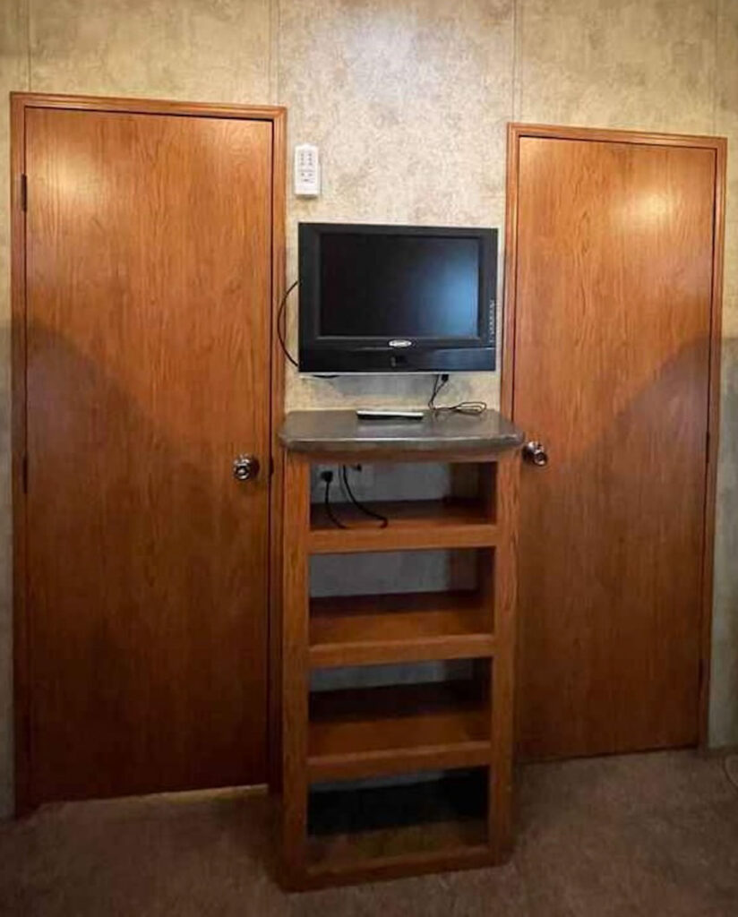a tv and stand in between two doors.