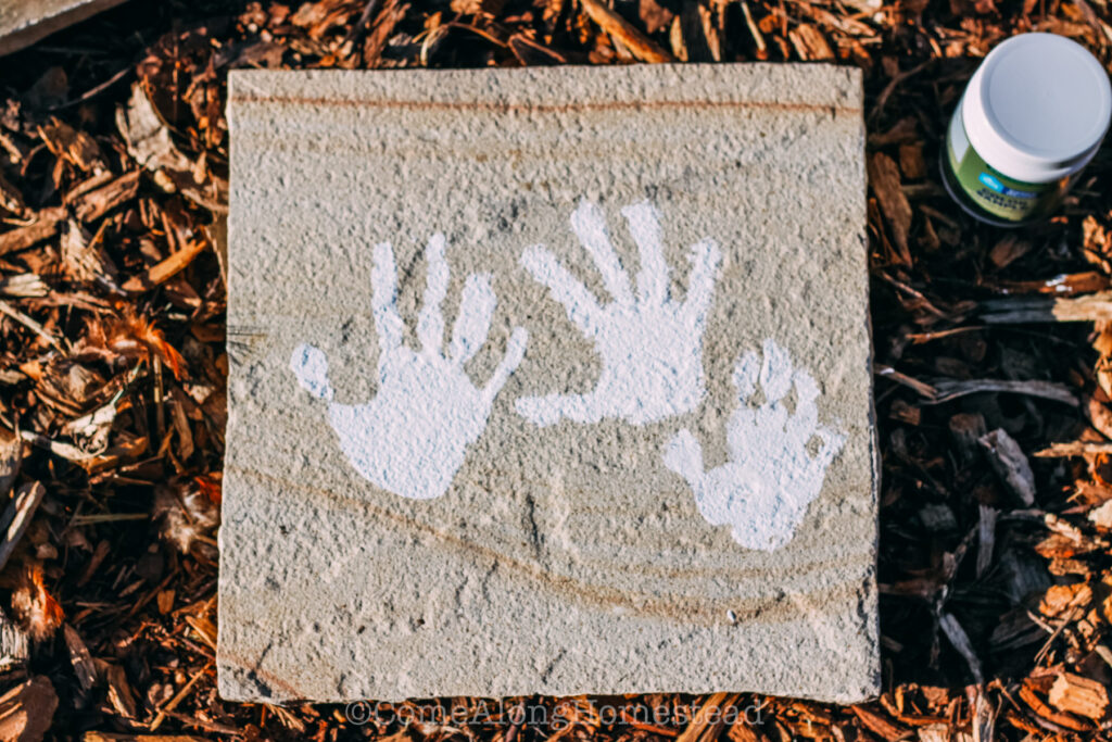 image of three white handprints on a stone paver