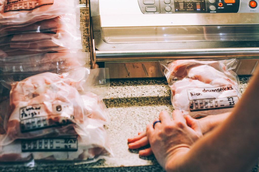 Vacuum sealing a bag of chicken pieces to preserve freshness for freezer storage.