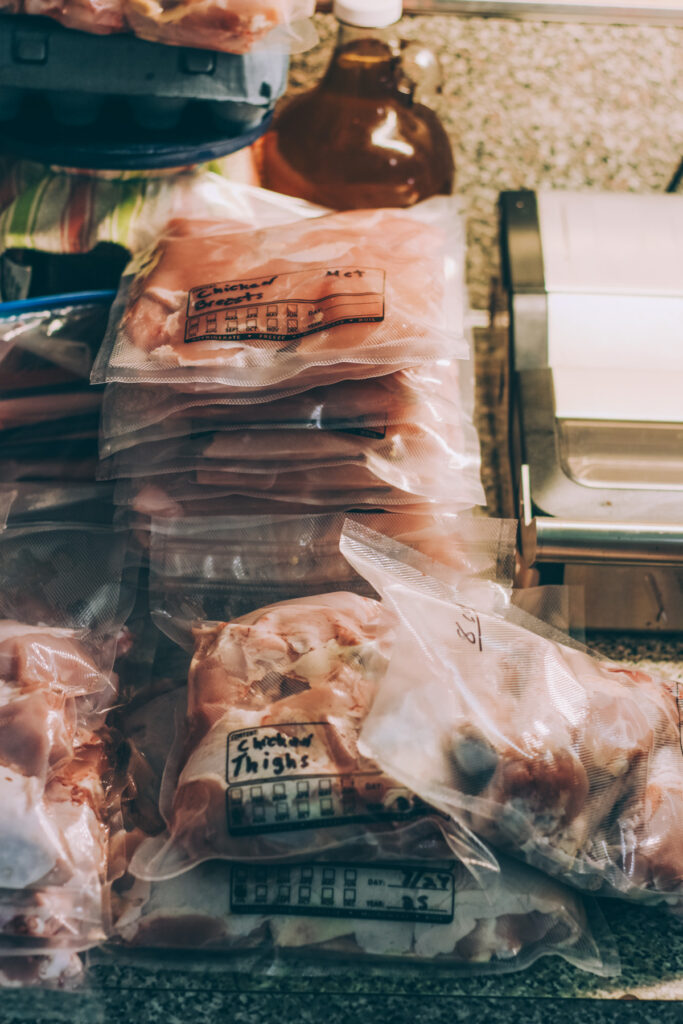 Pile of vacuum-sealed bags containing different cuts of chicken in various sizes, ready for freezer storage.